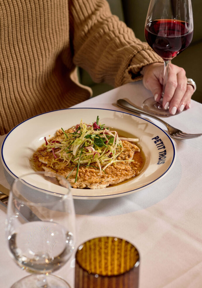 A woman enjoying chicken paillard at Petit Trois Aspen
