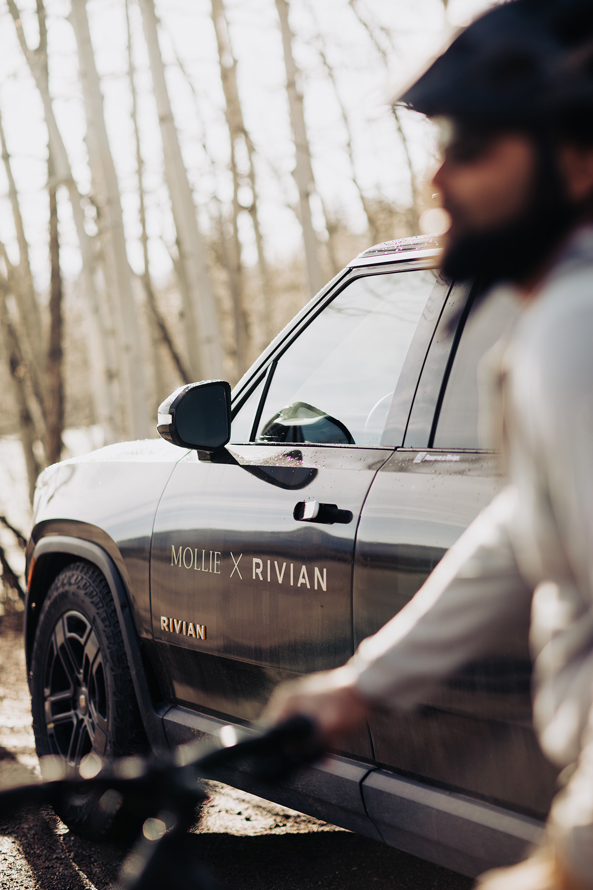 MOLLIE Aspen Rivian vehicle with a man mountain biking passed