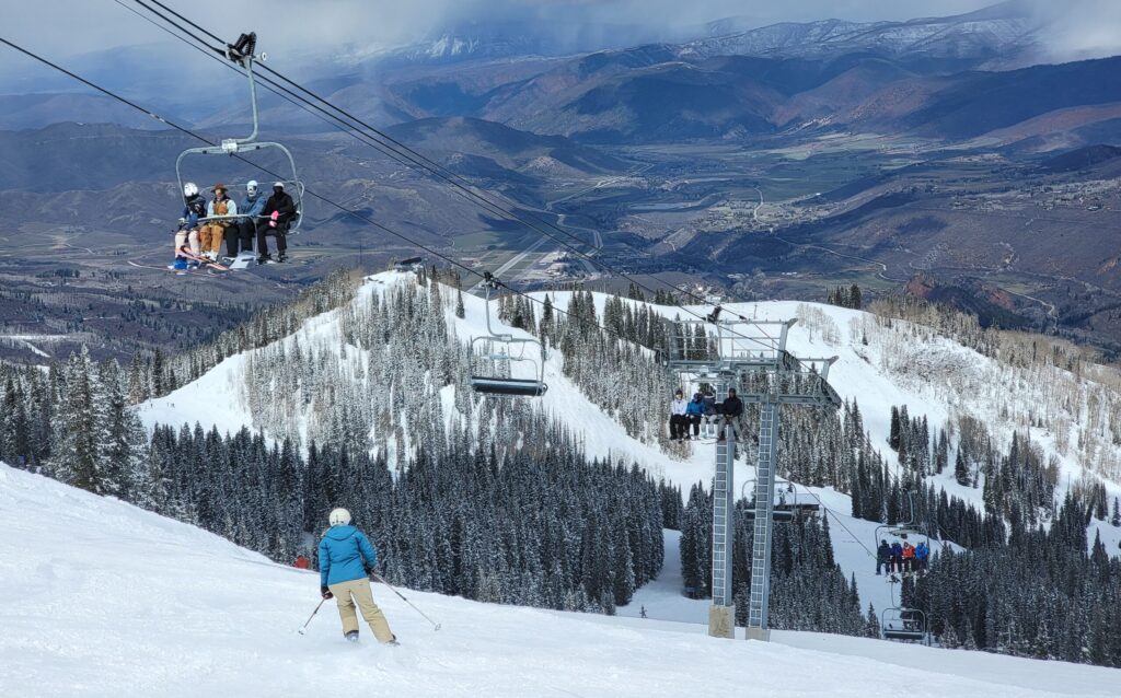 Skiers on a chairlift watching someone ski below them