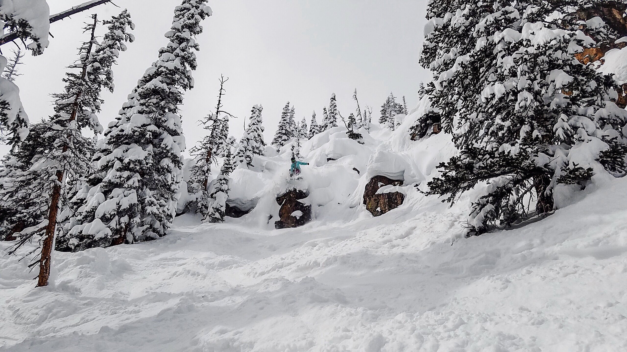 Skier going off a cliff on Ajax Mountain in fresh powder