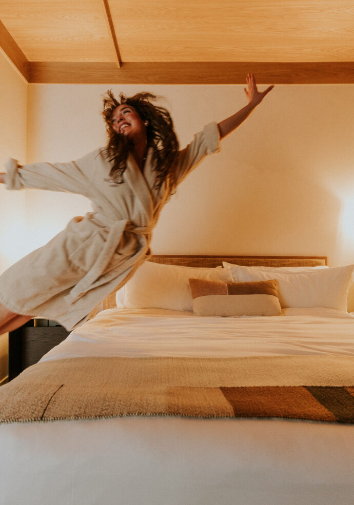 Guest jumping into MOLLIE Aspen bed in her robe