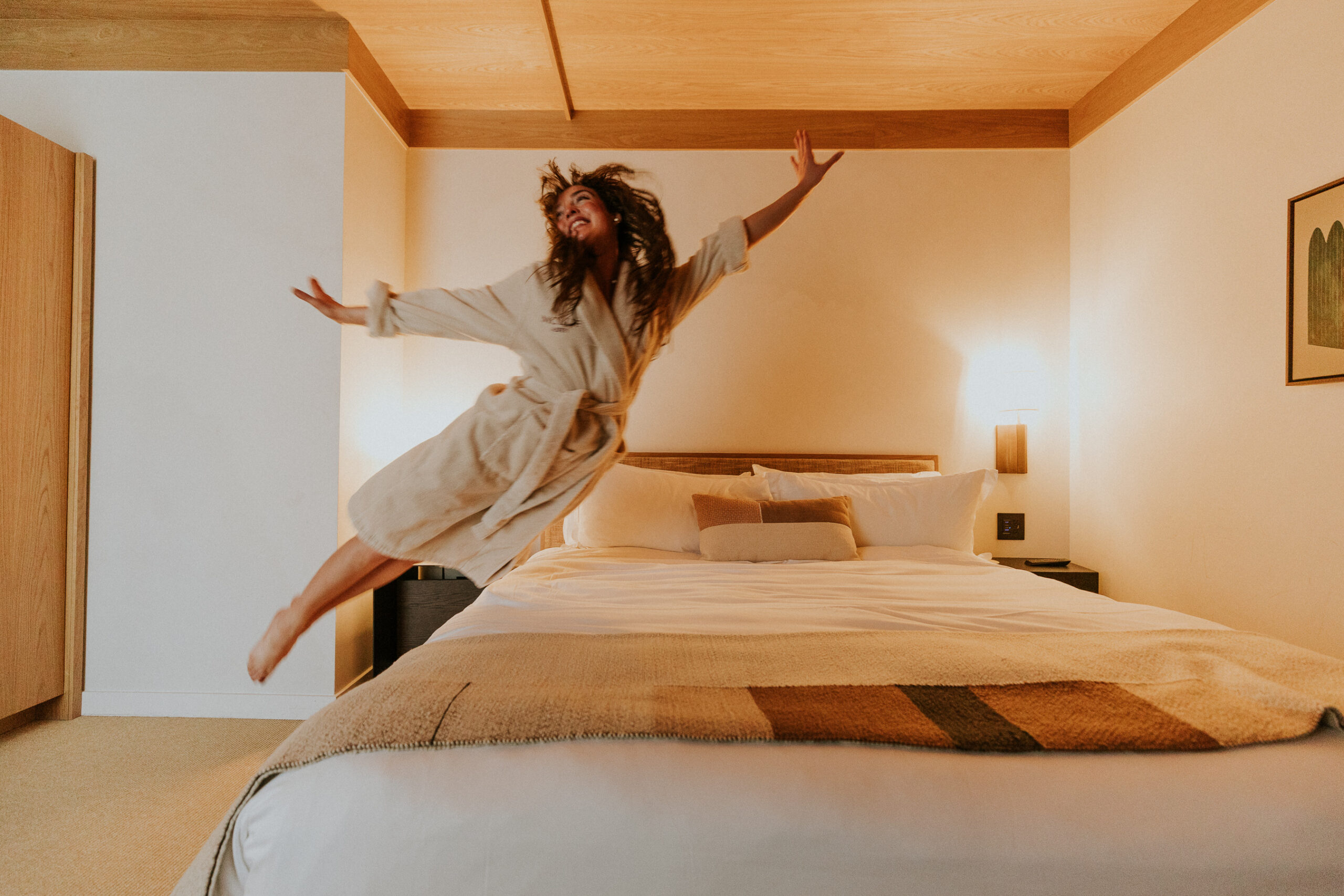 Guest jumping into MOLLIE Aspen bed in her robe